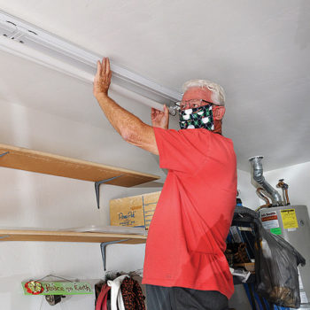 Terry Sterling, a volunteer on the Senior Village Helping Hands team, replaces a garage light for a Village member. This team offers many home and yard services, including computer consulting.