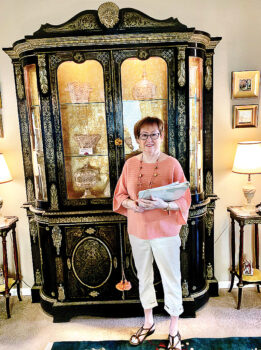 Sandi Newberry with a French Boulle Breakfront cabinet, Louis XIV style, circa 1850 with brass marquetry work and gilt-bronze mounts. Andre Boulle was the head cabinetmaker for King Louis XIV. Some Boulle original pieces of furniture were made around 1700 and can be seen at the Louvre Museum in Paris. During the last half of the 19th century, modern machine techniques were utilized to create large quantities of furniture made in the Boulle style with inlaid brass and bronze work on ebonized wood.