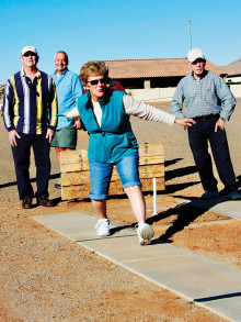 Fellow horseshoe players watch Sandra Best throw another ringer.