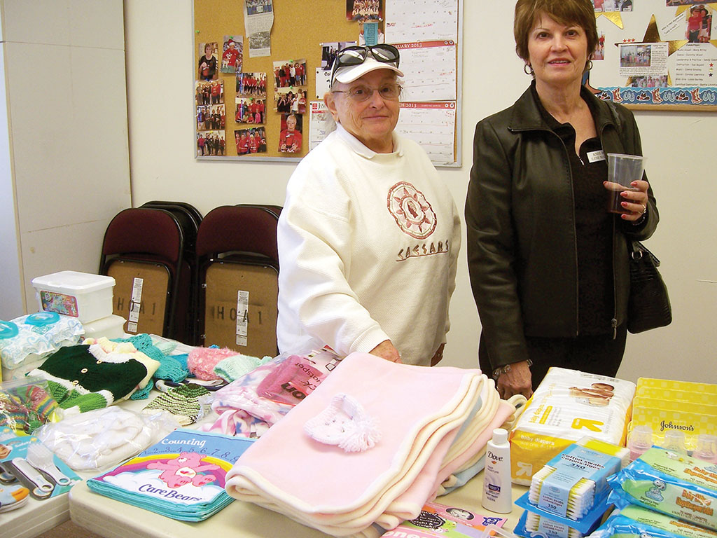 Members of Knit Wits admire all the donations for the baby shower.