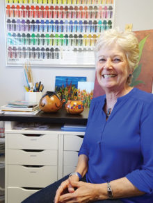 Nancy Springer sits in her studio with two newly completed gourds.