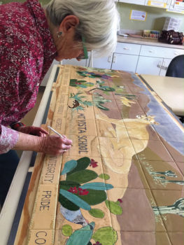 SaddleBrooke Pottery Club member Harriet Hason puts the finishing details on a desert scene mural prior to kiln firing the ceramic tiles. The mural is the club’s community service project for Mountain Vista School in Oracle.