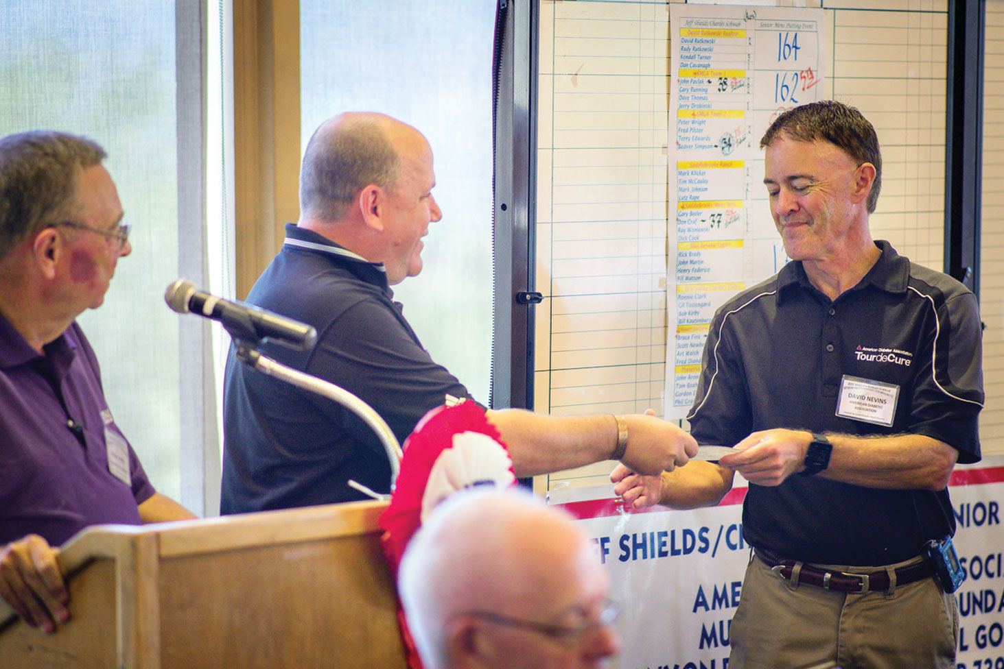 Harlan Hobbs looks on as Jeff Shields presents a check for $1000 to Dave Nevins of the Tucson office of the American Diabetes Association; Eric Peffer, photographer