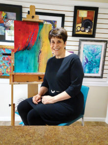 Teri Garner pauses with an in-progress work in her studio; photo by LaVerne Kyriss.