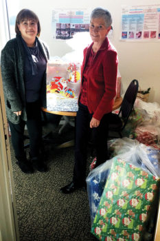 Carol Bowman (right) delivers Christmas presents to Brenda Garcia in the Impact office.