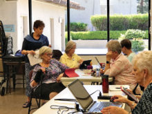 The ladies put down their knitting needles and listen intently to Linda Hood as she explains use of the knitting website, Ravelry.