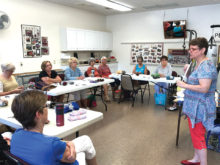 Tina Marie leads the group in learning how to make fingerless gloves.