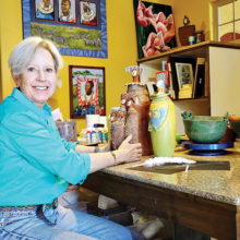 Harriet Hason shows a trio of her clay figures at the work table in her home studio.