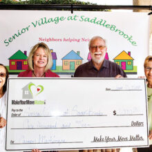 Realty Executives agent Beth Fedor (second from left) and her associate Jo Parsons (right) present a donation check to David Loendorf, Senior Village president, on behalf of their client Carmen Mackenzie (left).