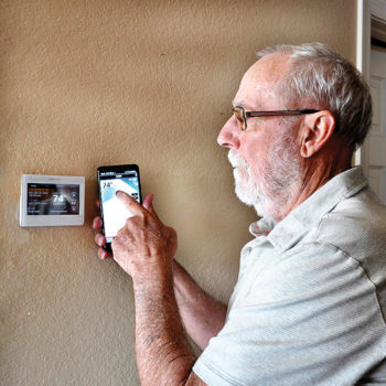 David Loendorf, Senior Village president, uses his cell phone to set the room temperature at home.