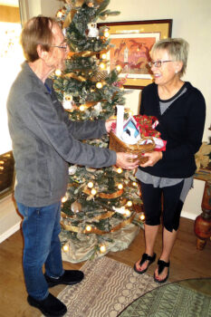 Senior Village volunteer Tom Borkovec presents member Elizabeth Conti with a surprise holiday gift basket.