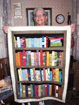 Ellen Wixom's sister Nancy with the "library" quilt Ellen made for her. The books in the quilt reflect Nancy's lifelong passions and interests.