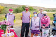 Larry McNamee, admiring the check-in table and gift bags prepared by wife, Loralee; Dan Nordhill; Event Chair, Loralee Horwedel; Matt Kambic; and Barbara Bloch, dressed in plum to honor cancer caregivers. (Photo by Bill George)