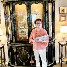 Sandi Newberry with a French Boulle Breakfront cabinet, Louis XIV style, circa 1850 with brass marquetry work and gilt-bronze mounts. Andre Boulle was the head cabinetmaker for King Louis XIV. Some Boulle original pieces of furniture were made around 1700 and can be seen at the Louvre Museum in Paris. During the last half of the 19th century, modern machine techniques were utilized to create large quantities of furniture made in the Boulle style with inlaid brass and bronze work on ebonized wood.