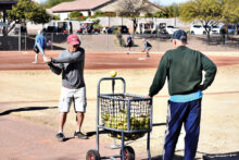 Skills Clinic Commissioner Peter Romeo watches Wayne Stafford practice his swing off the batting tee.