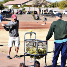 Skills Clinic Commissioner Peter Romeo watches Wayne Stafford practice his swing off the batting tee.