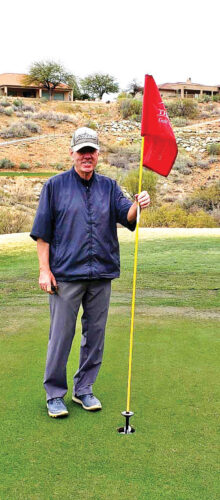 Shel Jahn next to his golf ball that is lodged in the hole on number 6 at the Preserve.